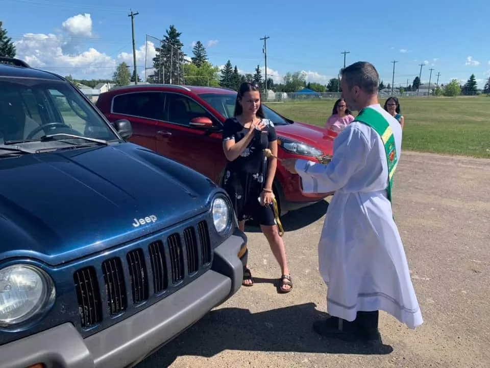 Deacon Ryan Sales blessing vehicles outdoors
